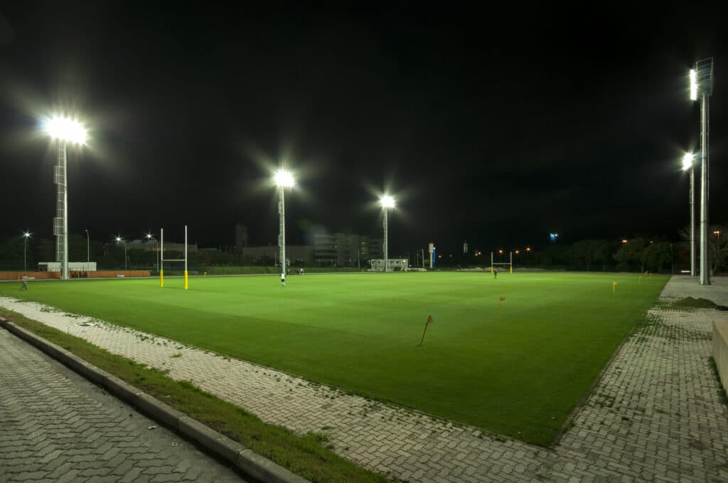 campo longo e verde iluminado por dois grandes e luminescente postes