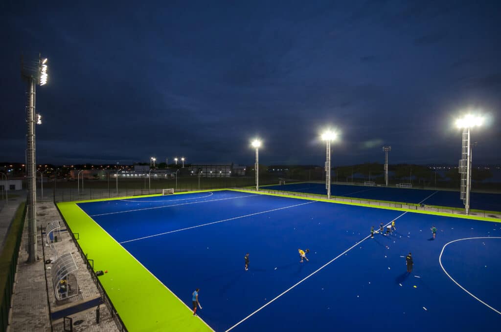 Campo de tennis azul iluminado por dois postes